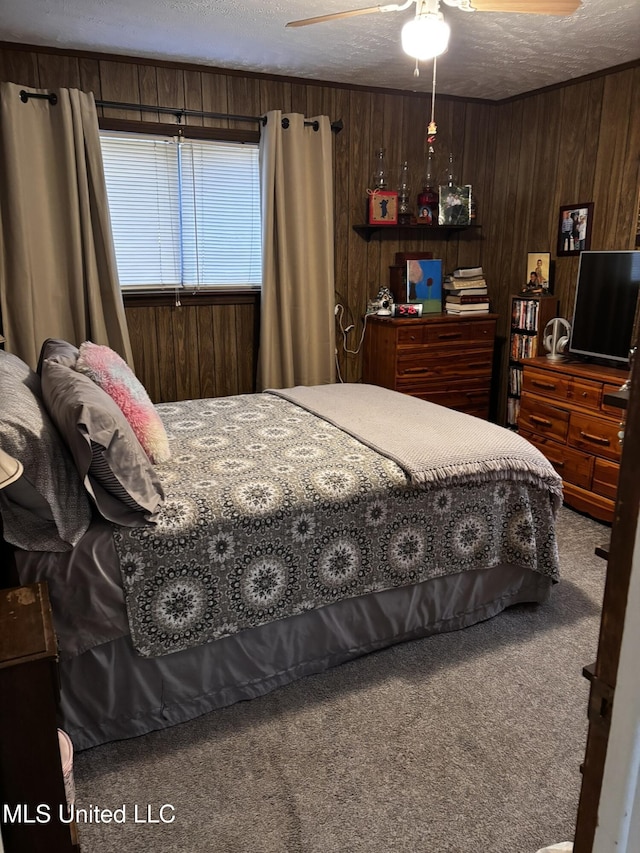 carpeted bedroom featuring ceiling fan, a textured ceiling, and wood walls