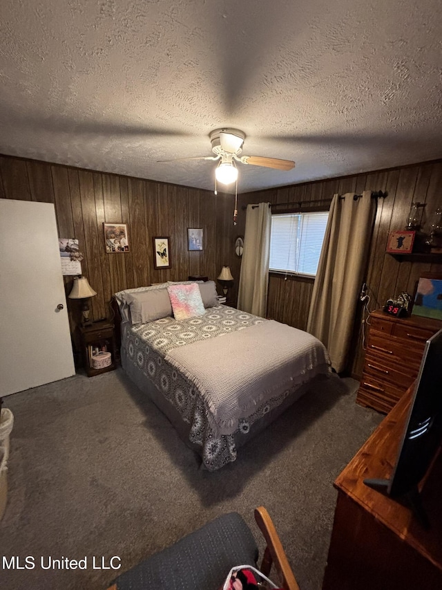 bedroom with a textured ceiling, wood walls, ceiling fan, and carpet