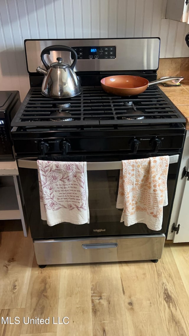 details with light hardwood / wood-style flooring and gas stove