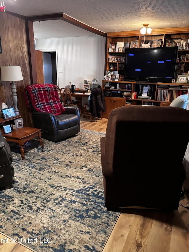 living room featuring hardwood / wood-style floors, built in features, a textured ceiling, and wood walls