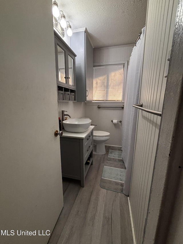 bathroom featuring hardwood / wood-style flooring, vanity, toilet, and a textured ceiling