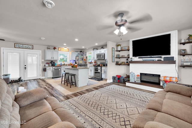 living room with french doors, light wood-type flooring, and ceiling fan