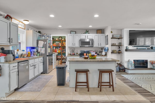 kitchen with sink, a kitchen island, stainless steel appliances, light stone counters, and a breakfast bar area