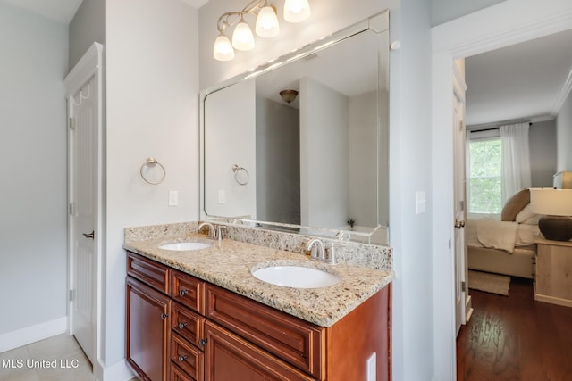 full bathroom with double vanity, a sink, baseboards, and ensuite bath