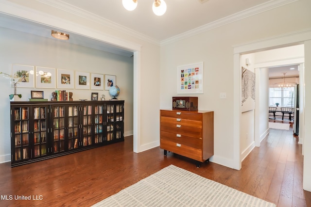 living area with an inviting chandelier, wood finished floors, ornamental molding, and baseboards