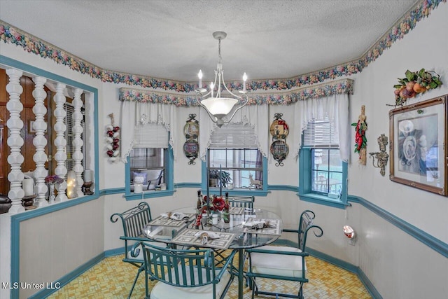 dining space with a textured ceiling and a notable chandelier