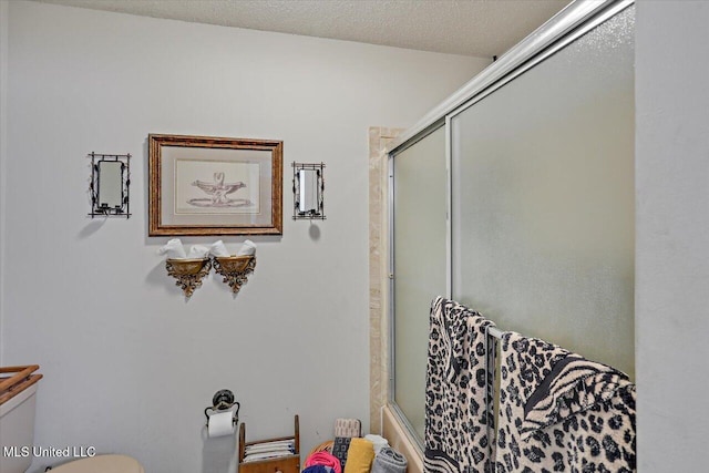 bathroom with shower / bath combination with glass door, a textured ceiling, and toilet