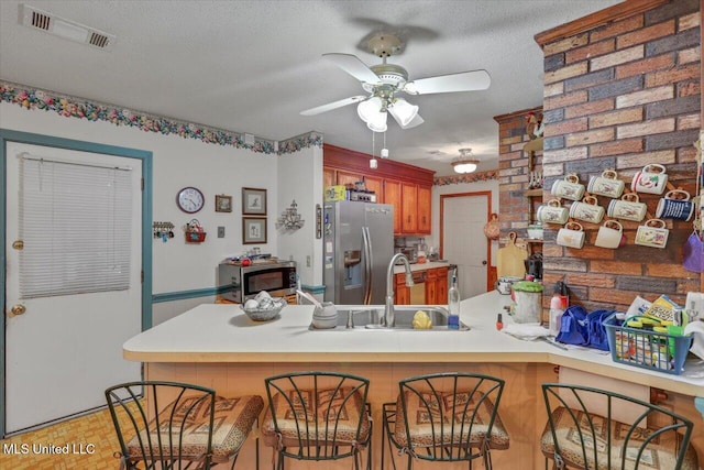 kitchen with kitchen peninsula, appliances with stainless steel finishes, a textured ceiling, ceiling fan, and sink