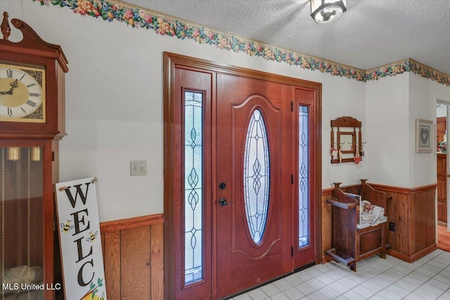 foyer with light tile patterned floors, a textured ceiling, plenty of natural light, and wooden walls