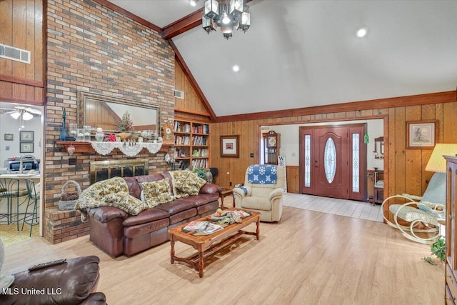 living room featuring beamed ceiling, light wood-type flooring, a fireplace, and wooden walls