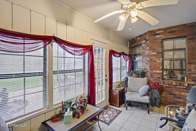 interior space featuring light tile patterned floors, ceiling fan, and brick wall