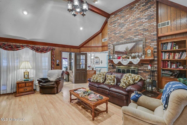 living room featuring wood walls, vaulted ceiling with beams, light wood-type flooring, a fireplace, and built in features