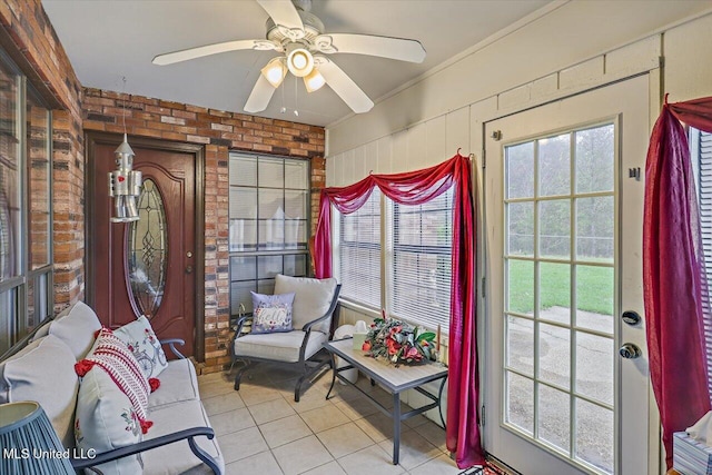 living area with ceiling fan, light tile patterned flooring, and brick wall