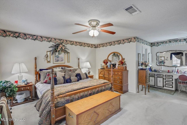 bedroom with ceiling fan, light colored carpet, and a textured ceiling