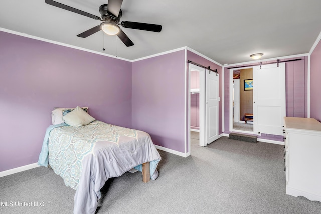 carpeted bedroom featuring a barn door, baseboards, a ceiling fan, and crown molding