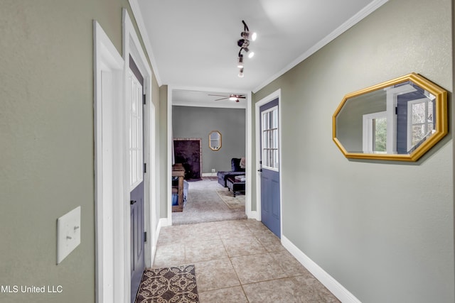 hall with light tile patterned floors, baseboards, plenty of natural light, and crown molding