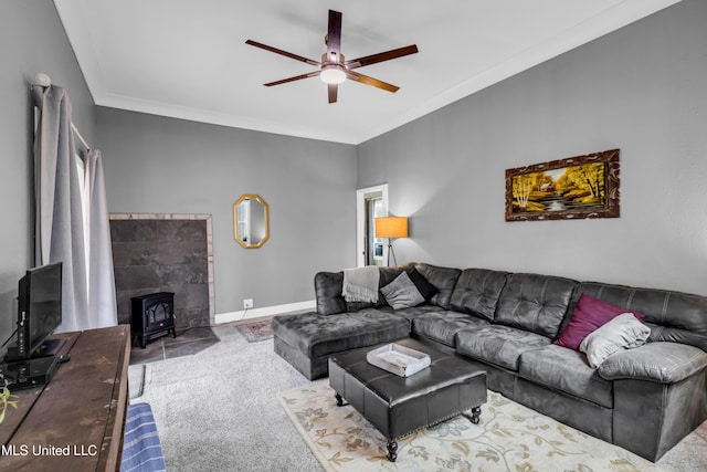 carpeted living area with baseboards, ceiling fan, a wood stove, and crown molding