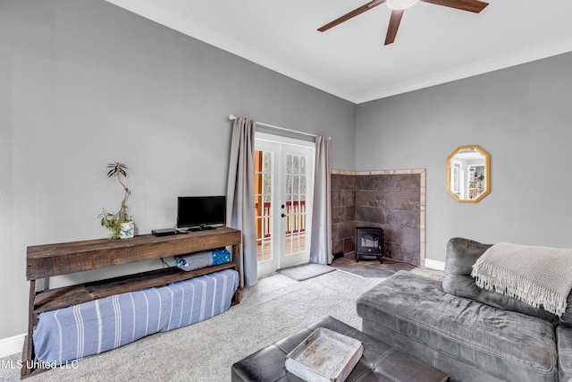 living room featuring crown molding, baseboards, carpet, french doors, and a wood stove