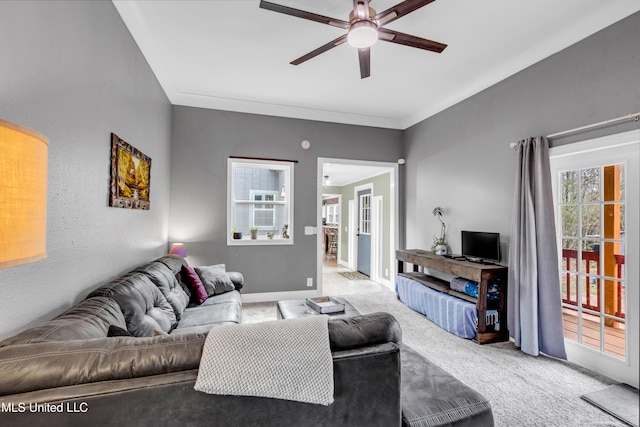 carpeted living area featuring baseboards, crown molding, and a ceiling fan