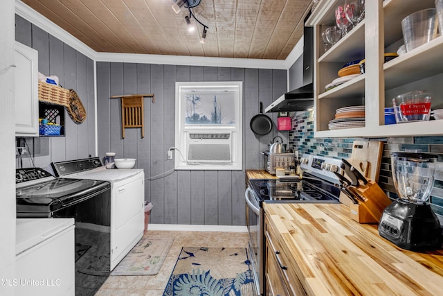 kitchen with washing machine and clothes dryer, decorative backsplash, electric stove, wall chimney exhaust hood, and butcher block counters