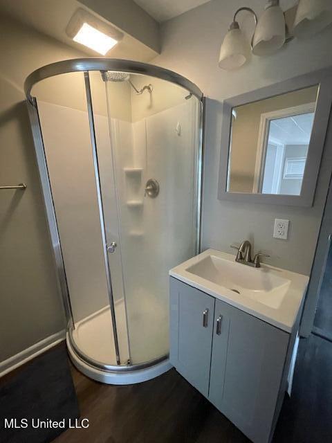 bathroom featuring vanity, an enclosed shower, and wood-type flooring