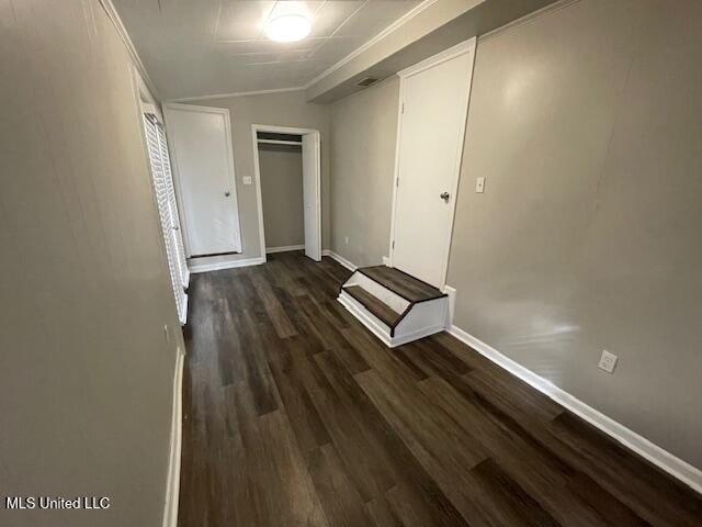 corridor with vaulted ceiling, dark hardwood / wood-style floors, and ornamental molding