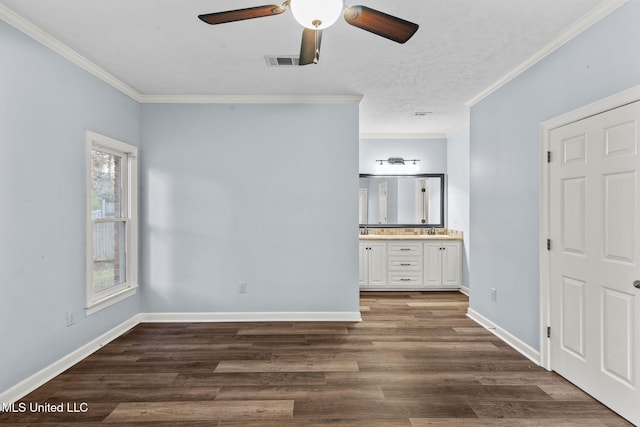 unfurnished bedroom featuring dark wood-type flooring, ensuite bathroom, sink, crown molding, and ceiling fan