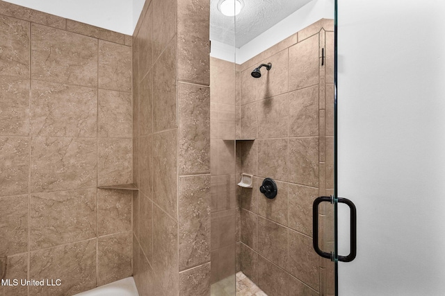 bathroom with a shower with shower door and a textured ceiling