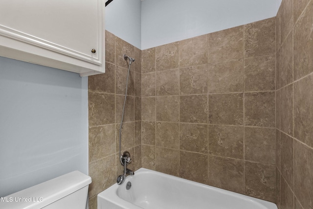 bathroom featuring tiled shower / bath combo and toilet