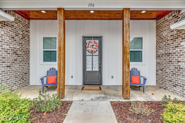 property entrance featuring board and batten siding and brick siding