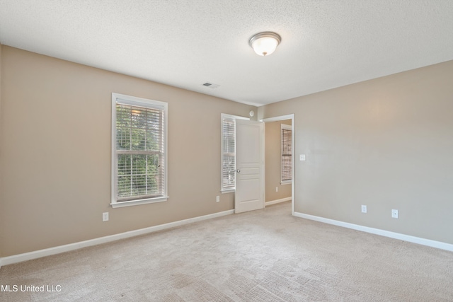 unfurnished room featuring light colored carpet and a textured ceiling