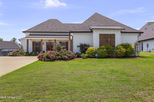 view of front of property featuring brick siding, a shingled roof, a front lawn, and a standing seam roof