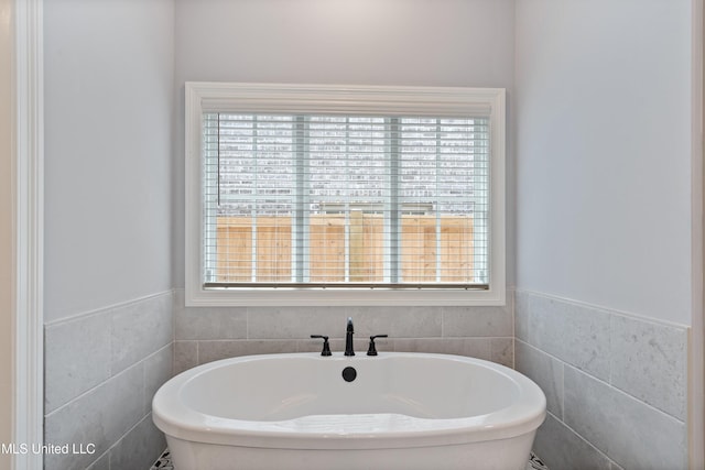 bathroom featuring a bathtub and tile walls