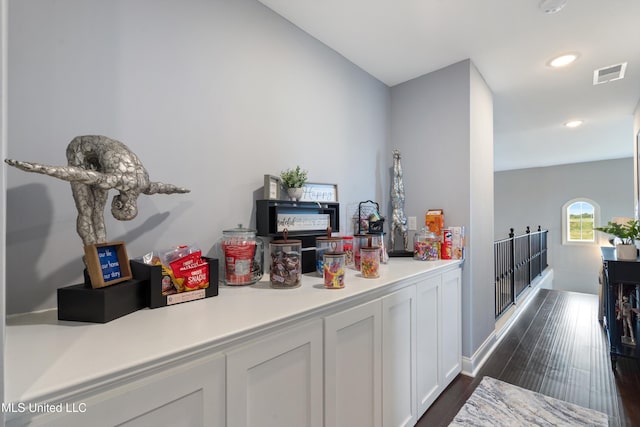 bar featuring white cabinetry and dark hardwood / wood-style flooring