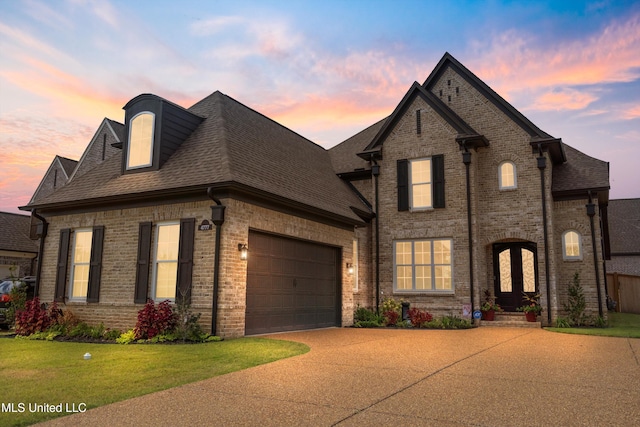 french provincial home featuring a garage and a lawn