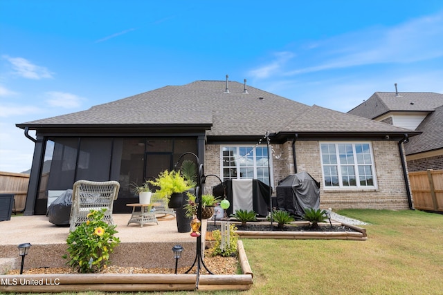 rear view of property with a yard, a patio, and a sunroom