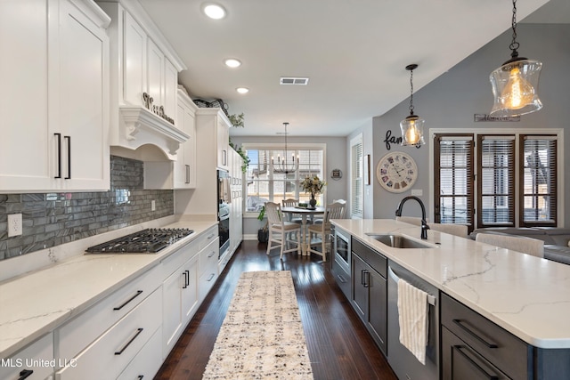 kitchen featuring pendant lighting, white cabinetry, a kitchen island with sink, and sink