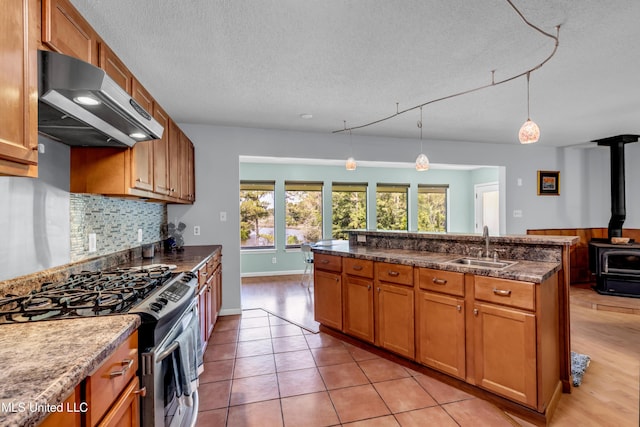 2529 Windward Dr, Gautier, MS 39553 - kitchen with stainless steel range with gas stovetop, exhaust hood, a sink, a textured ceiling, and a wood stove