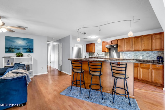 2529 Windward Dr, Gautier, MS 39553 - kitchen with freestanding refrigerator, light wood-style flooring, a breakfast bar, brown cabinetry, and open floor plan