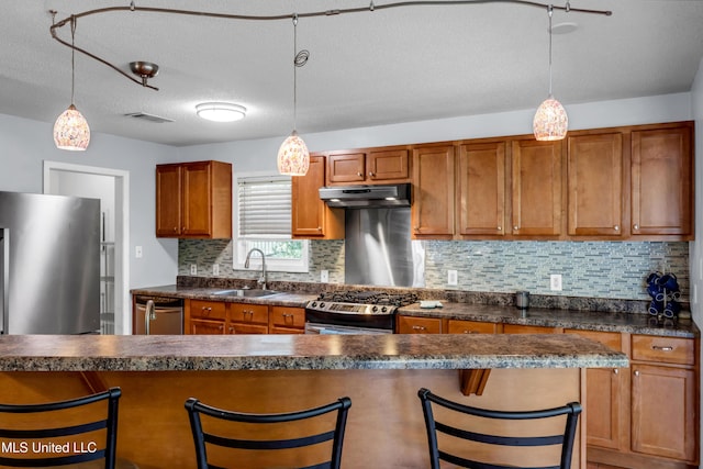 2529 Windward Dr, Gautier, MS 39553 - kitchen with stainless steel appliances, under cabinet range hood, a sink, dark countertops, and tasteful backsplash
