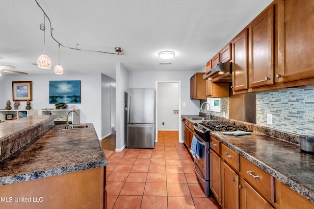 2529 Windward Dr, Gautier, MS 39553 - kitchen featuring stainless steel appliances, under cabinet range hood, a sink, brown cabinetry, and a textured ceiling