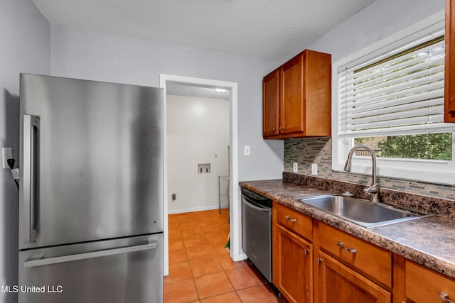 2529 Windward Dr, Gautier, MS 39553 - kitchen featuring appliances with stainless steel finishes, a sink, light tile patterned flooring, dark countertops, and tasteful backsplash