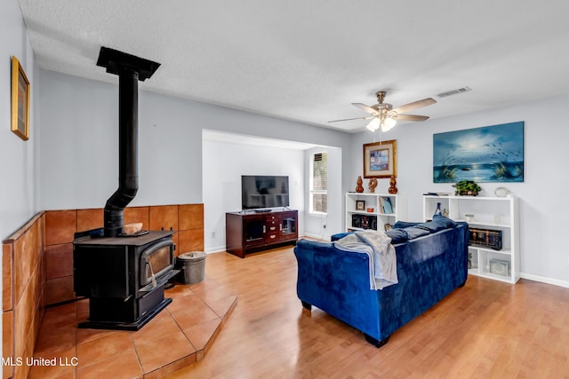 2529 Windward Dr, Gautier, MS 39553 - living area featuring a wood stove, a ceiling fan, and light wood-style flooring