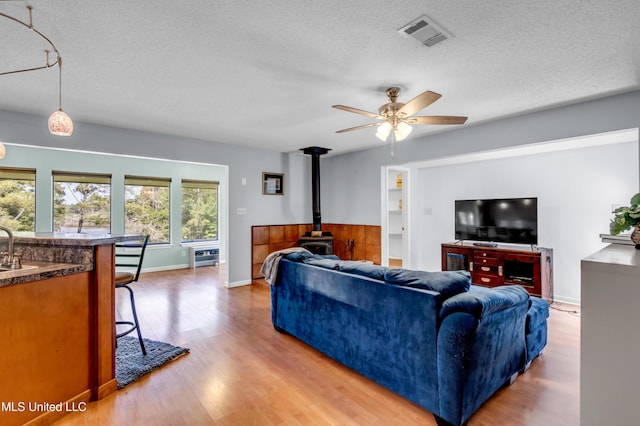 2529 Windward Dr, Gautier, MS 39553 - living area with a wood stove, a textured ceiling, wood finished floors, a ceiling fan, and baseboards