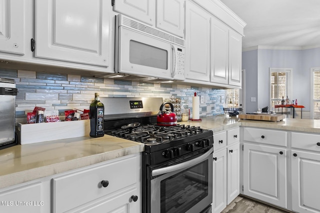 kitchen with tasteful backsplash, gas stove, white cabinets, and crown molding