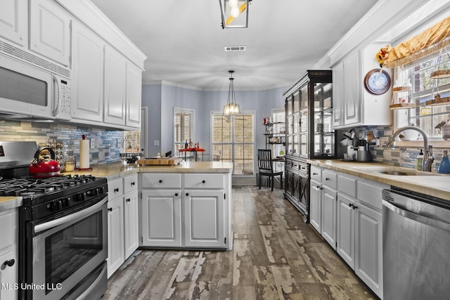 kitchen featuring sink, white cabinetry, pendant lighting, stainless steel appliances, and hardwood / wood-style floors