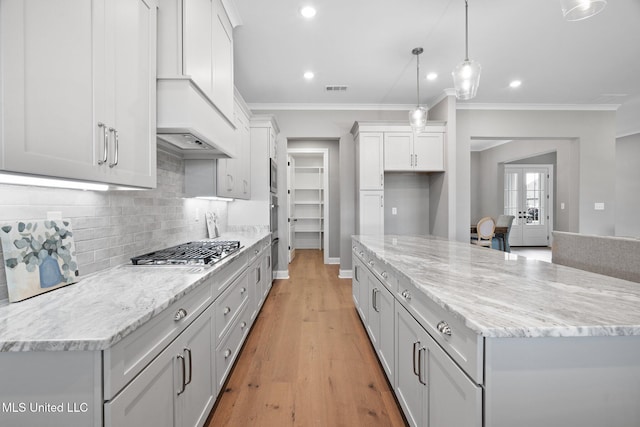 2115 Livingston Way, Hernando, MS 38632 - kitchen featuring appliances with stainless steel finishes, decorative backsplash, crown molding, a center island, and light stone countertops