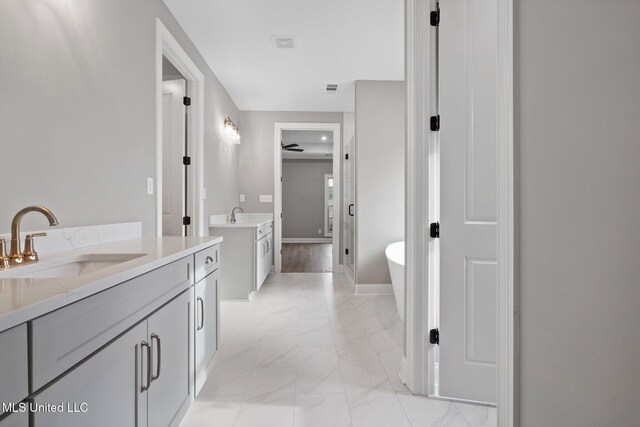 2115 Livingston Way, Hernando, MS 38632 - bathroom featuring two vanities, marble look tile flooring, a soaking tub, and baseboards
