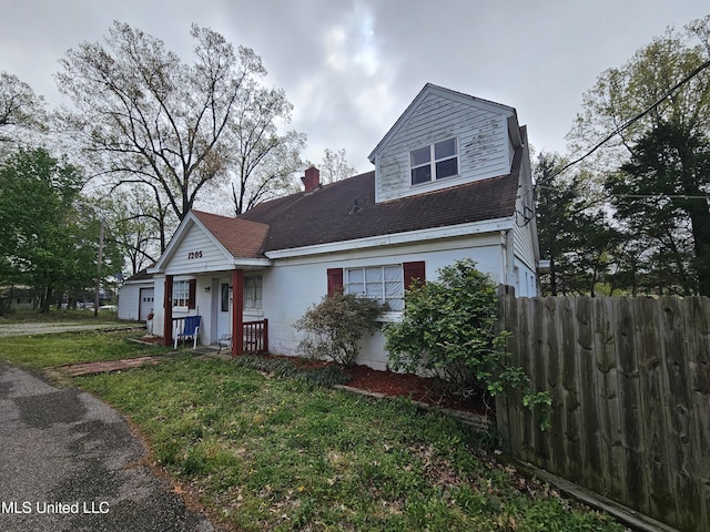view of front of home with a chimney, fence, a front lawn, and concrete block siding