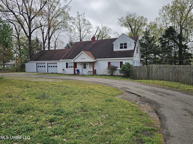 view of front facade with driveway, fence, and a front lawn